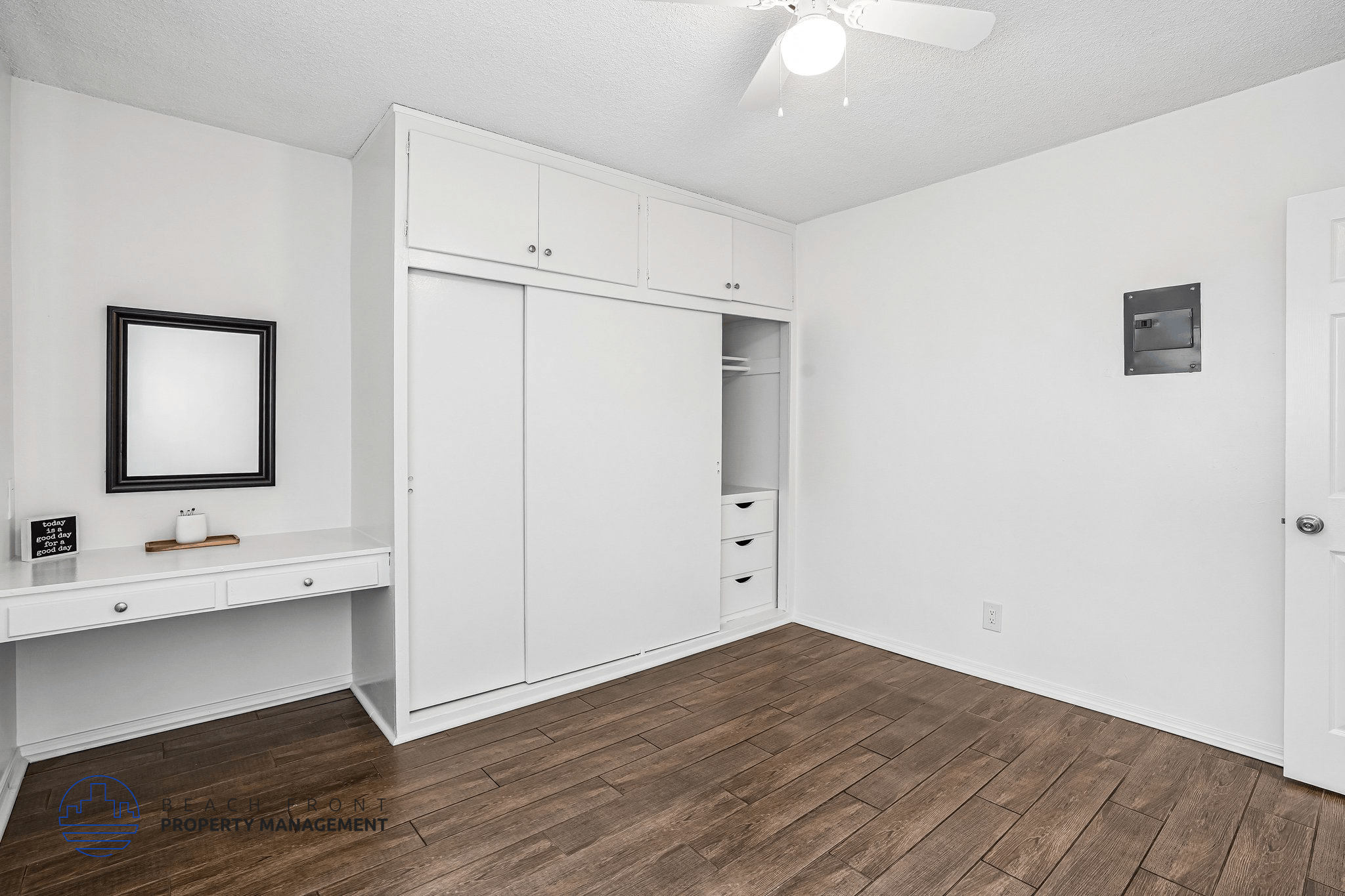 A room with a white ceiling, a white door, a white cabinet, and a brown floor.